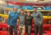 4 personnes sourient devant une pile de kayak