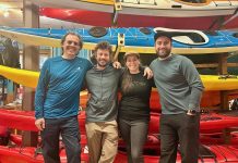 4 personnes sourient devant une pile de kayak