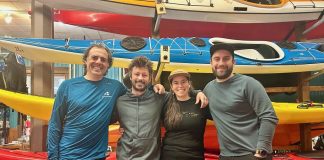4 personnes sourient devant une pile de kayak